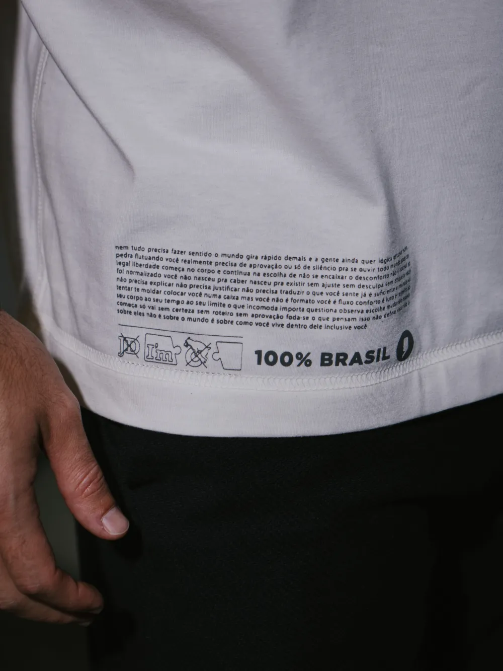 Barra interna de uma camiseta com as instruções de lavagem impressas direto no tecido, ao lado do selo 100% Brasil. Não há etiqueta costurada.