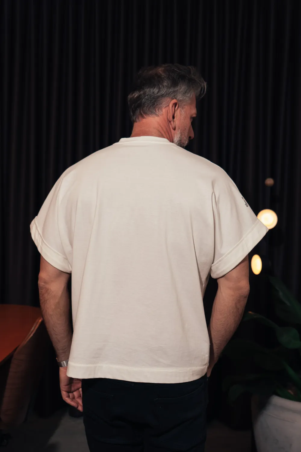 O mesmo modelo de costas, mostrando o comprimento e o corte reto da peça.