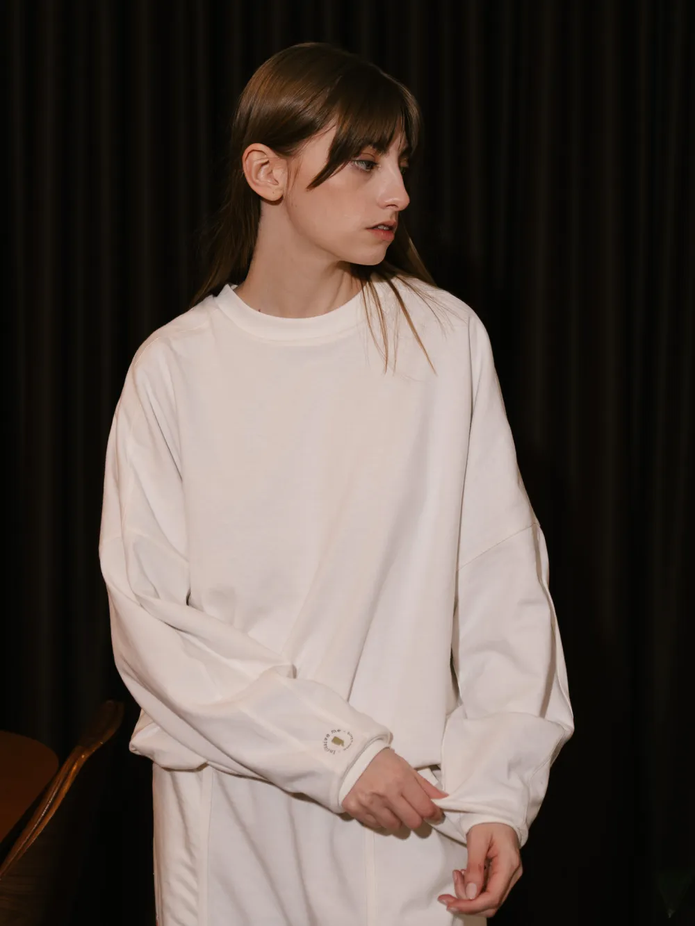 A mesma peça vestida do lado off-white, de frente, com as mãos à frente do corpo.