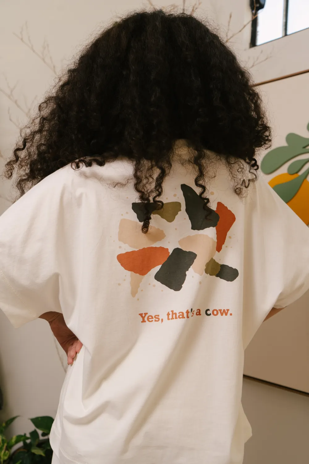Pessoa de costas com a camiseta, mostrando a estampa inteira e a frase abaixo dela.